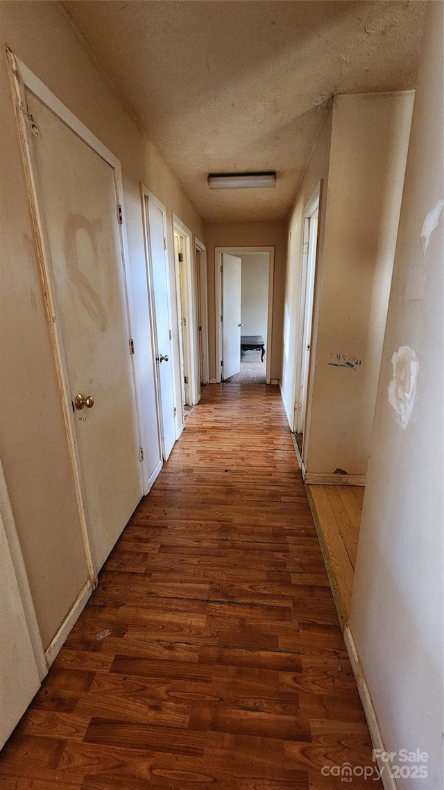 corridor with wood-type flooring and a textured ceiling