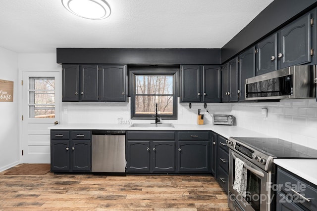 kitchen featuring stainless steel appliances, hardwood / wood-style flooring, sink, and decorative backsplash