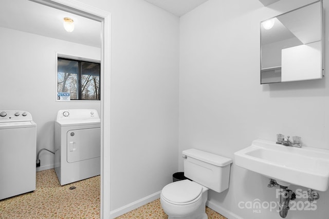 bathroom with washing machine and dryer, sink, and toilet