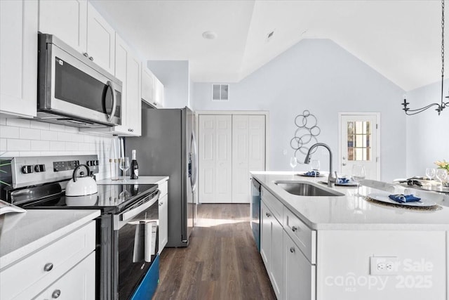 kitchen featuring sink, hanging light fixtures, stainless steel appliances, an island with sink, and white cabinets