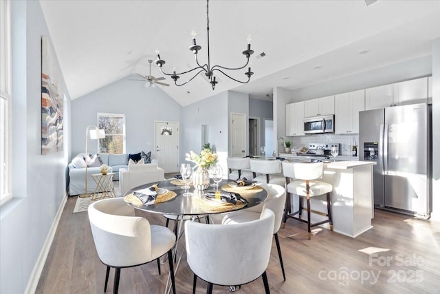 dining area with lofted ceiling, ceiling fan with notable chandelier, and light wood-type flooring