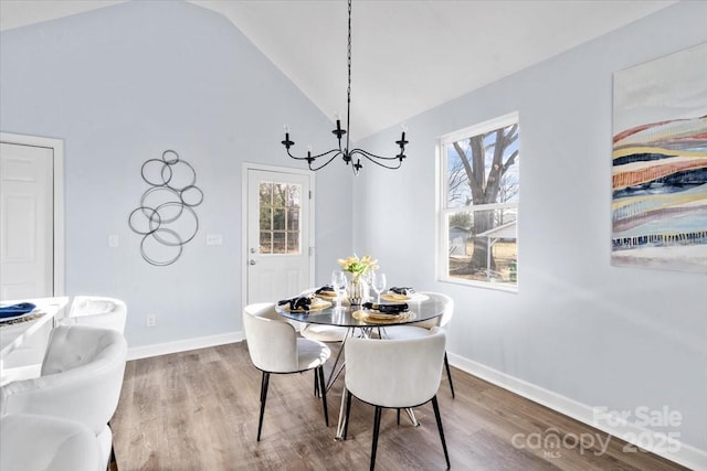 dining area featuring hardwood / wood-style floors, high vaulted ceiling, and a chandelier