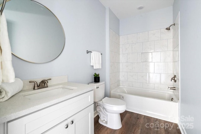 full bathroom featuring vanity, hardwood / wood-style flooring, tiled shower / bath combo, and toilet