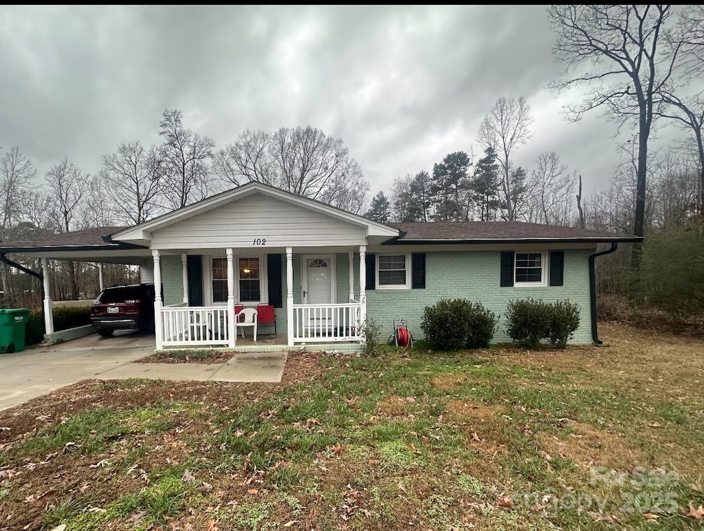 ranch-style house featuring a carport, a front yard, and covered porch