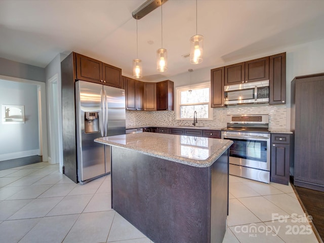 kitchen with pendant lighting, sink, stainless steel appliances, light stone countertops, and a kitchen island