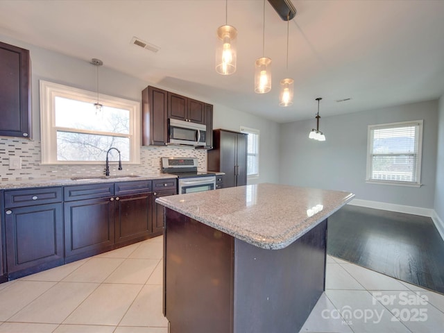 kitchen featuring dark brown cabinetry, sink, stainless steel appliances, and a kitchen island