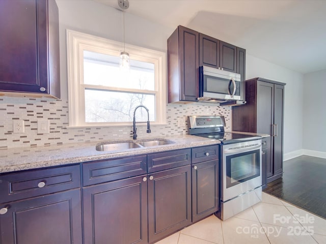 kitchen with pendant lighting, sink, light tile patterned floors, stainless steel appliances, and light stone countertops