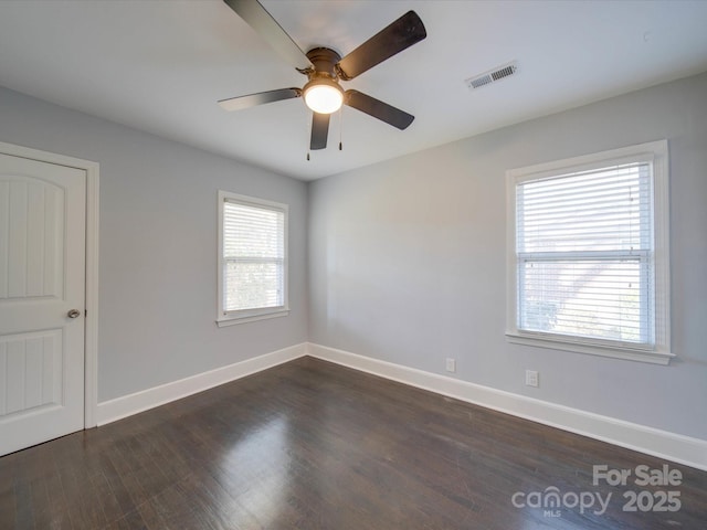 spare room featuring dark wood-type flooring, ceiling fan, and plenty of natural light