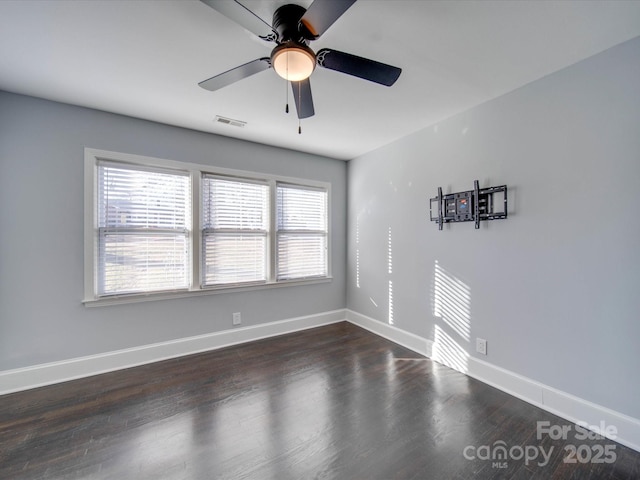 unfurnished room featuring ceiling fan, a healthy amount of sunlight, and dark hardwood / wood-style floors