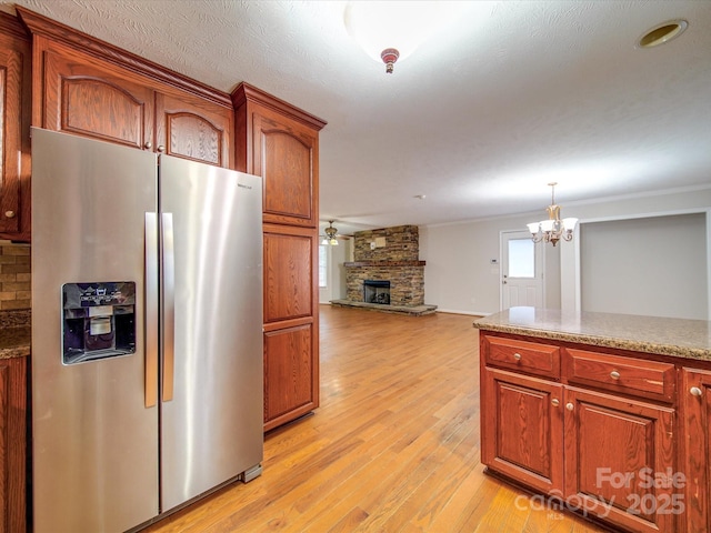 kitchen with stainless steel fridge with ice dispenser, pendant lighting, ceiling fan, a fireplace, and light hardwood / wood-style floors