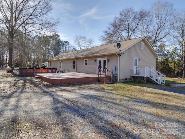 back of property featuring french doors, a deck, and a jacuzzi