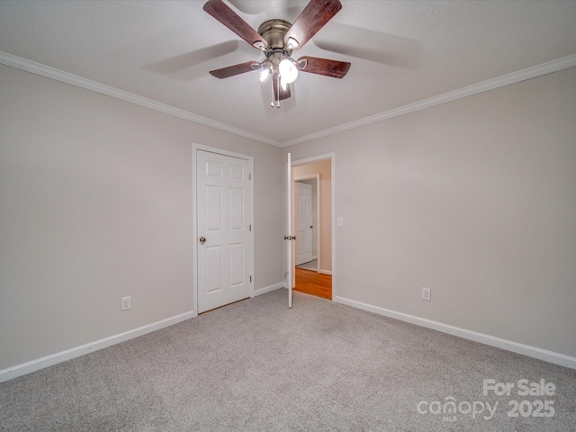 carpeted empty room featuring ornamental molding and ceiling fan