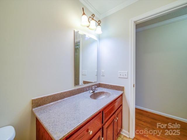 bathroom featuring vanity, wood-type flooring, ornamental molding, and toilet