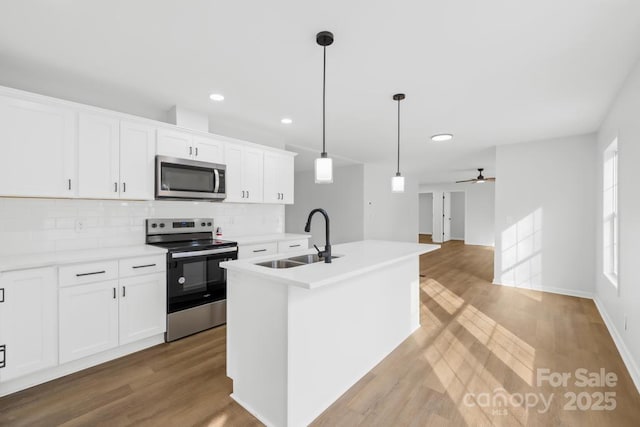 kitchen with decorative light fixtures, white cabinetry, sink, a kitchen island with sink, and stainless steel appliances