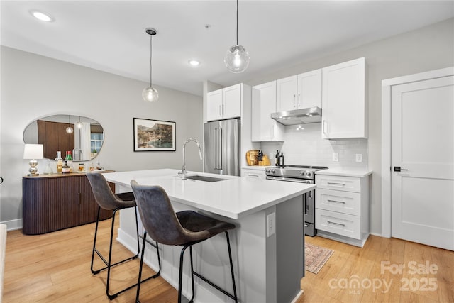 kitchen with sink, white cabinets, hanging light fixtures, a kitchen island with sink, and stainless steel appliances