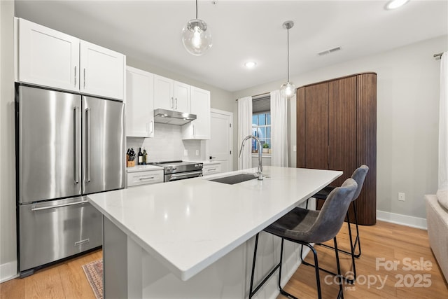 kitchen featuring pendant lighting, stainless steel appliances, and a center island with sink