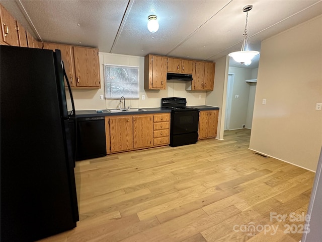 kitchen with pendant lighting, sink, light wood-type flooring, black appliances, and a textured ceiling