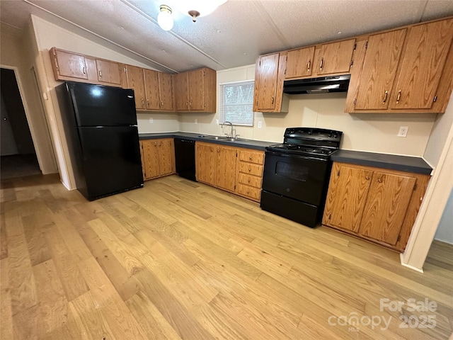 kitchen featuring sink, vaulted ceiling, black appliances, and light wood-type flooring