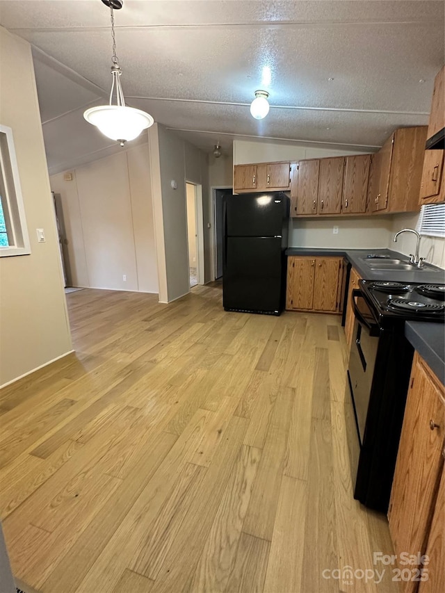 kitchen with decorative light fixtures, sink, light wood-type flooring, black appliances, and a textured ceiling