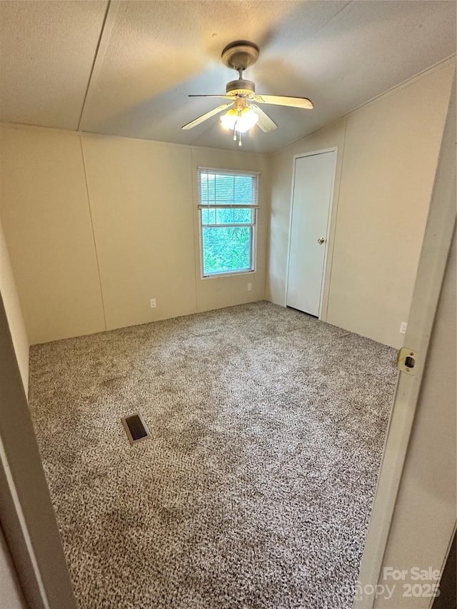 carpeted spare room featuring a textured ceiling and ceiling fan