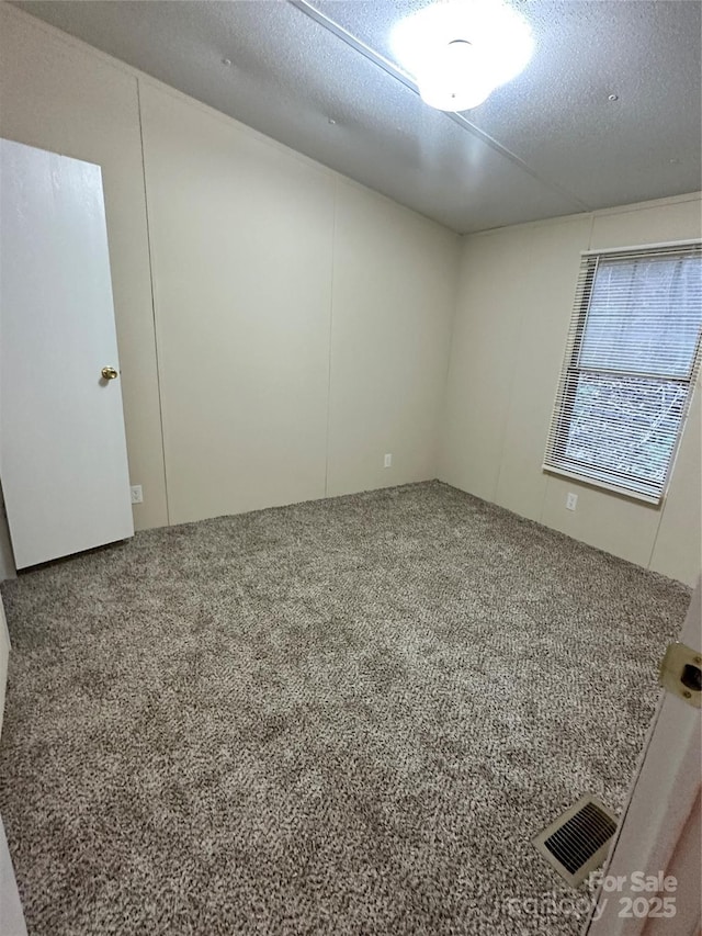 carpeted spare room with a textured ceiling