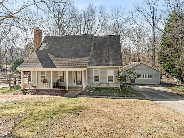 view of front facade with an outbuilding, a garage, a front lawn, and a porch