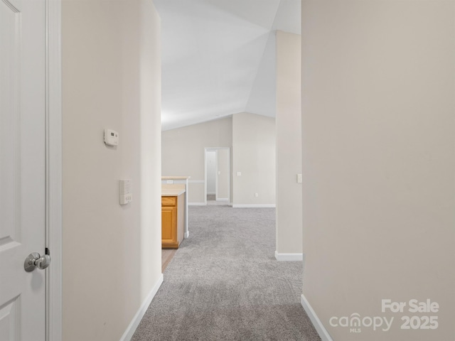 corridor featuring vaulted ceiling and carpet flooring