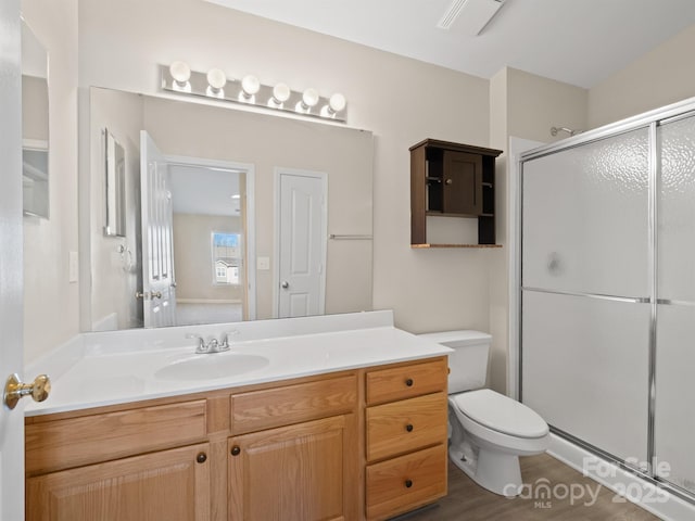 bathroom with hardwood / wood-style flooring, vanity, toilet, and an enclosed shower