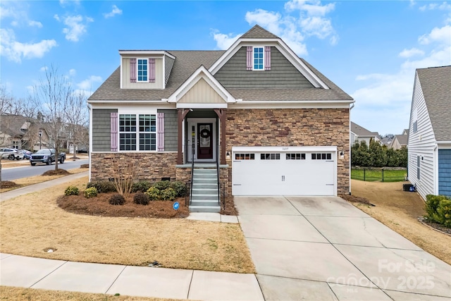 craftsman-style house with a garage, driveway, roof with shingles, and stone siding