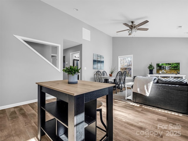 dining space featuring ceiling fan, vaulted ceiling, and wood-type flooring