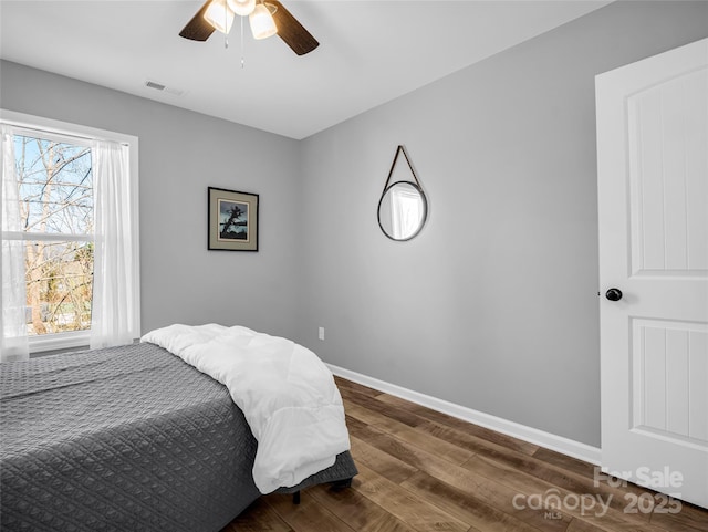 bedroom featuring dark wood-type flooring, ceiling fan, and multiple windows