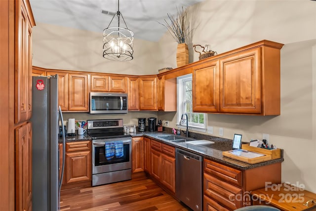 kitchen featuring dark wood-type flooring, sink, hanging light fixtures, appliances with stainless steel finishes, and a notable chandelier