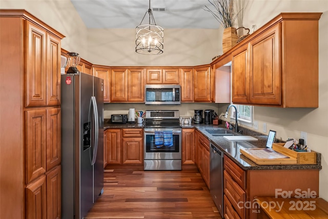 kitchen with dark wood-type flooring, sink, a chandelier, hanging light fixtures, and appliances with stainless steel finishes