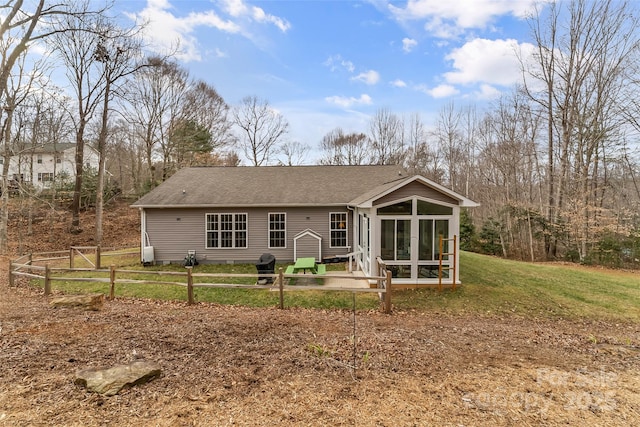 back of property with a sunroom and a lawn