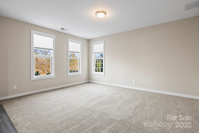 spare room featuring carpet, visible vents, and baseboards