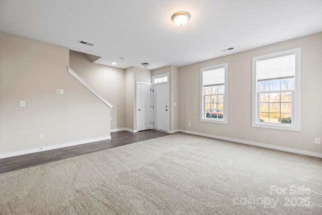 interior space with baseboards, visible vents, and dark carpet