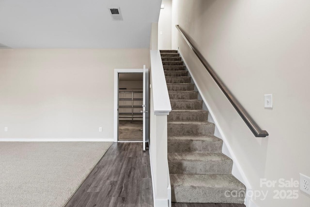 stairs featuring wood finished floors, visible vents, and baseboards