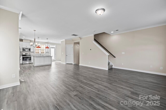 unfurnished living room featuring baseboards, stairway, dark wood finished floors, and crown molding