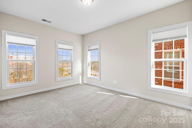 unfurnished room with carpet, visible vents, and baseboards