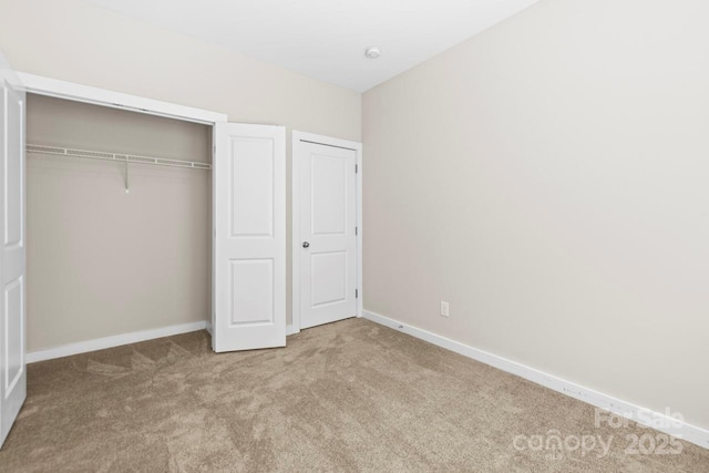 unfurnished bedroom with light carpet, a closet, and baseboards