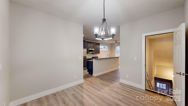 unfurnished dining area featuring an inviting chandelier and light hardwood / wood-style flooring