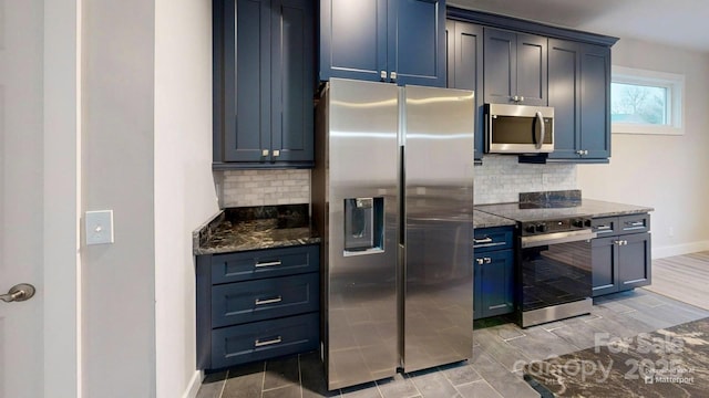 kitchen with dark stone countertops, appliances with stainless steel finishes, blue cabinets, and backsplash