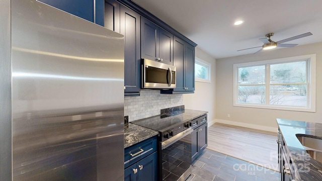 kitchen featuring blue cabinetry, ceiling fan, dark tile patterned floors, appliances with stainless steel finishes, and backsplash