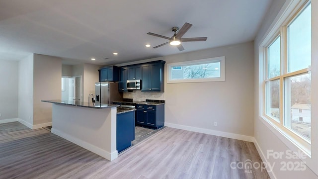 kitchen featuring tasteful backsplash, appliances with stainless steel finishes, blue cabinetry, and light hardwood / wood-style floors