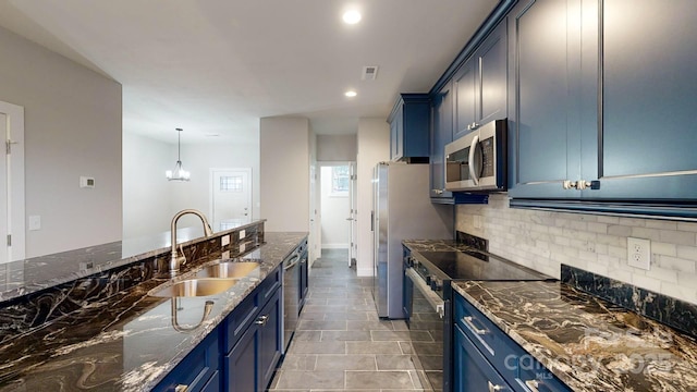 kitchen featuring blue cabinets, sink, hanging light fixtures, dark stone countertops, and appliances with stainless steel finishes