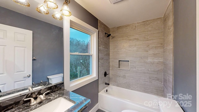 full bathroom featuring vanity, tiled shower / bath combo, a wealth of natural light, and toilet