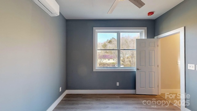 spare room featuring hardwood / wood-style floors, a wall mounted air conditioner, and ceiling fan