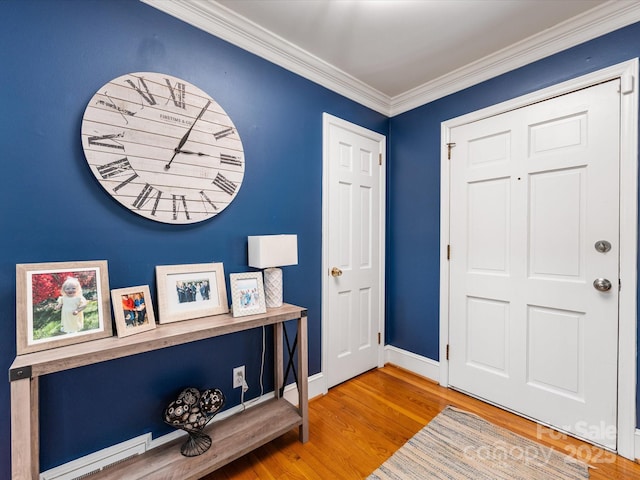 foyer entrance with ornamental molding and wood-type flooring