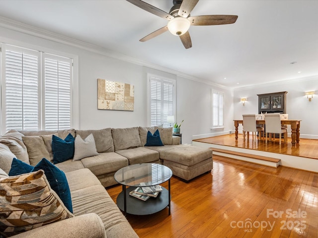 living room with ornamental molding, ceiling fan, and light wood-type flooring