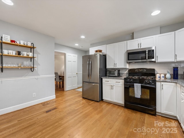 kitchen featuring white cabinetry, appliances with stainless steel finishes, backsplash, and light hardwood / wood-style flooring